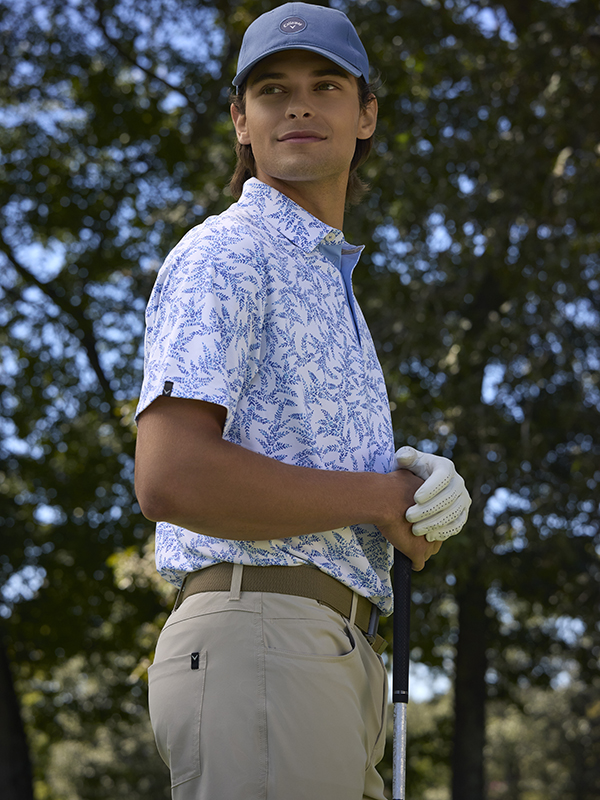 Model Wearing Mens Callaway Apparel White Polo with Blue Pattern and Khaki Pants and a Blue Cap